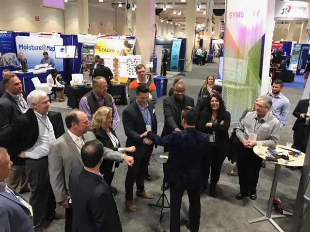 Trade show magician in Boston David Hall performing magic and mind reading for attendees at a crowded convention booth
